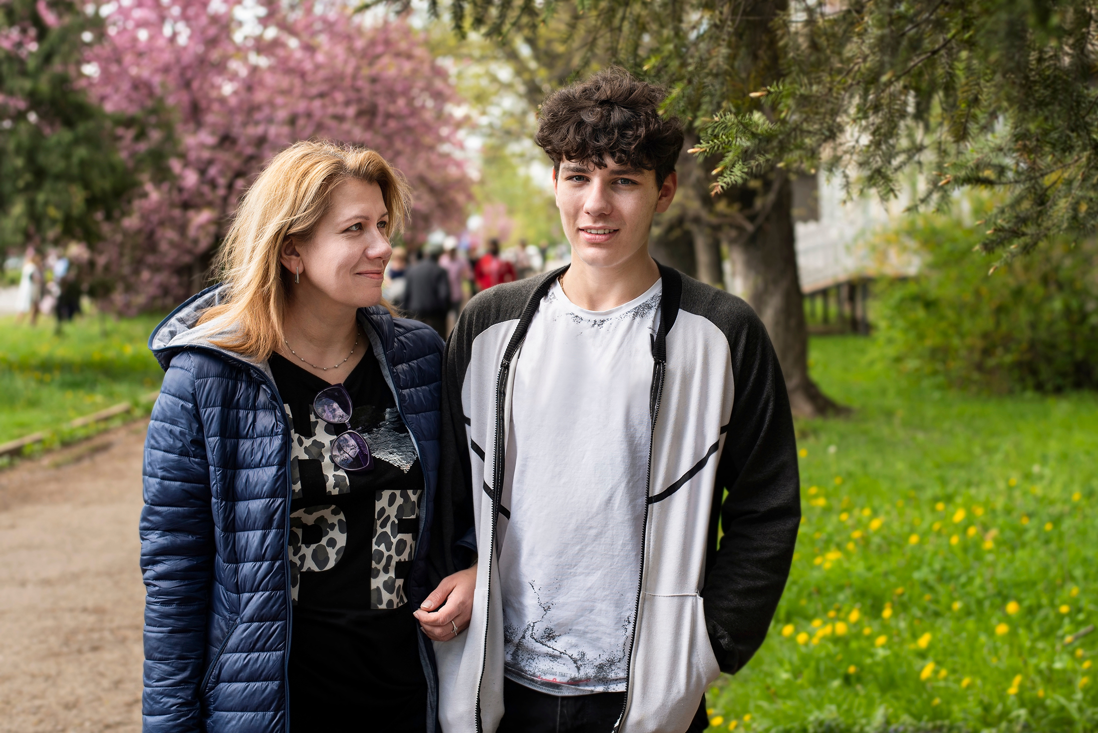 Woman,Walks,With,Her,Teenage,Son,And,Communicate,,Laugh.,A Woman walks with her teenage son and communicate, laugh. A mother looks at her son with love, pride and understanding. The concept of a good relationship between mother and teenage son